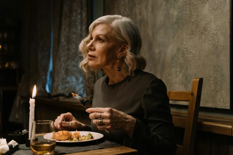 a woman sitting at a table with a plate of food, by Adam Marczyński, pexels contest winner, silver haired, angelina stroganova, lit from the side, ready to eat