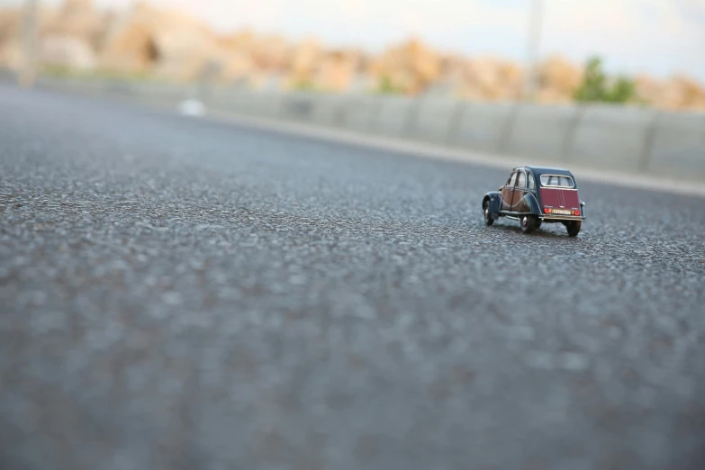 a toy car is sitting in the middle of the road, unsplash, photorealism, detailed medium format photo, photorealistic”