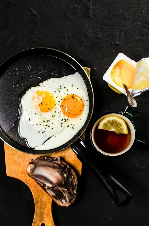 a frying pan filled with eggs on top of a wooden cutting board, a still life, trending on pexels, dau-al-set, maple syrup sea, black, oysters, manuka