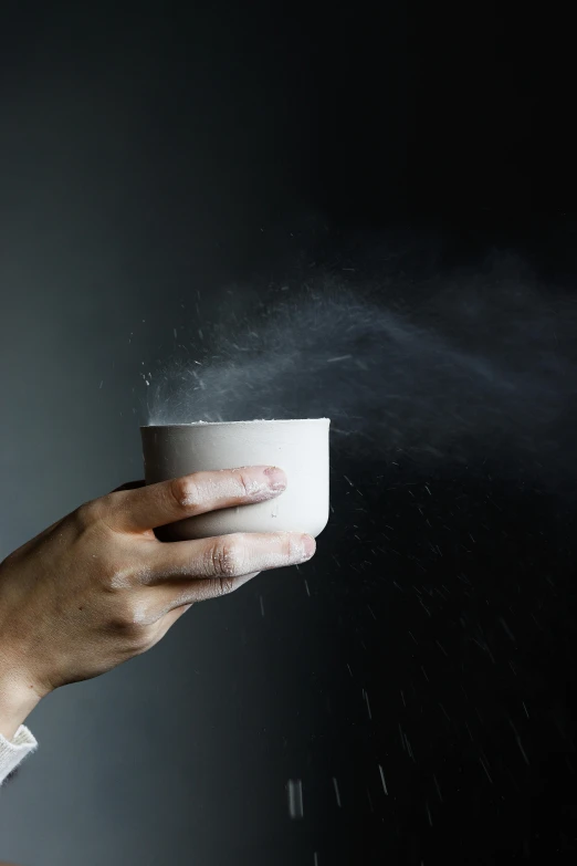 a close up of a person holding a cup of coffee, by Daniel Seghers, cold mist black background, organic ceramic white, dust mist, pot