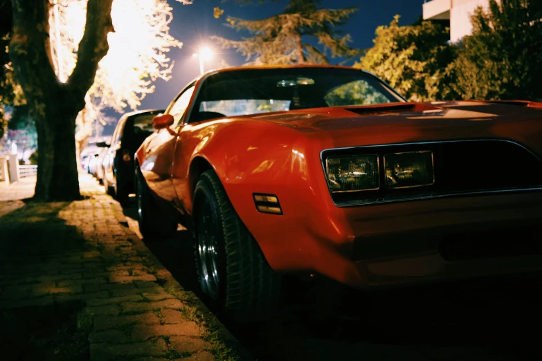 a red car parked on the side of the road, pexels contest winner, photorealism, summer night, muscle cars, 7 0 s cinestill, bumblebee