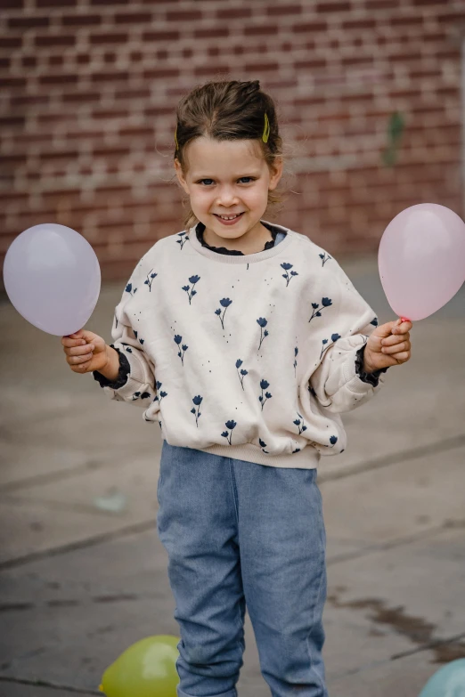 a little girl holding a bunch of balloons, dressed casually, wearing sweatshirt, subtle detailing, soft cool tones