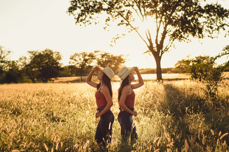 a couple of women standing next to each other in a field, a picture, by Julia Pishtar, pexels contest winner, backlit ears, cowgirl, twins, avatar image