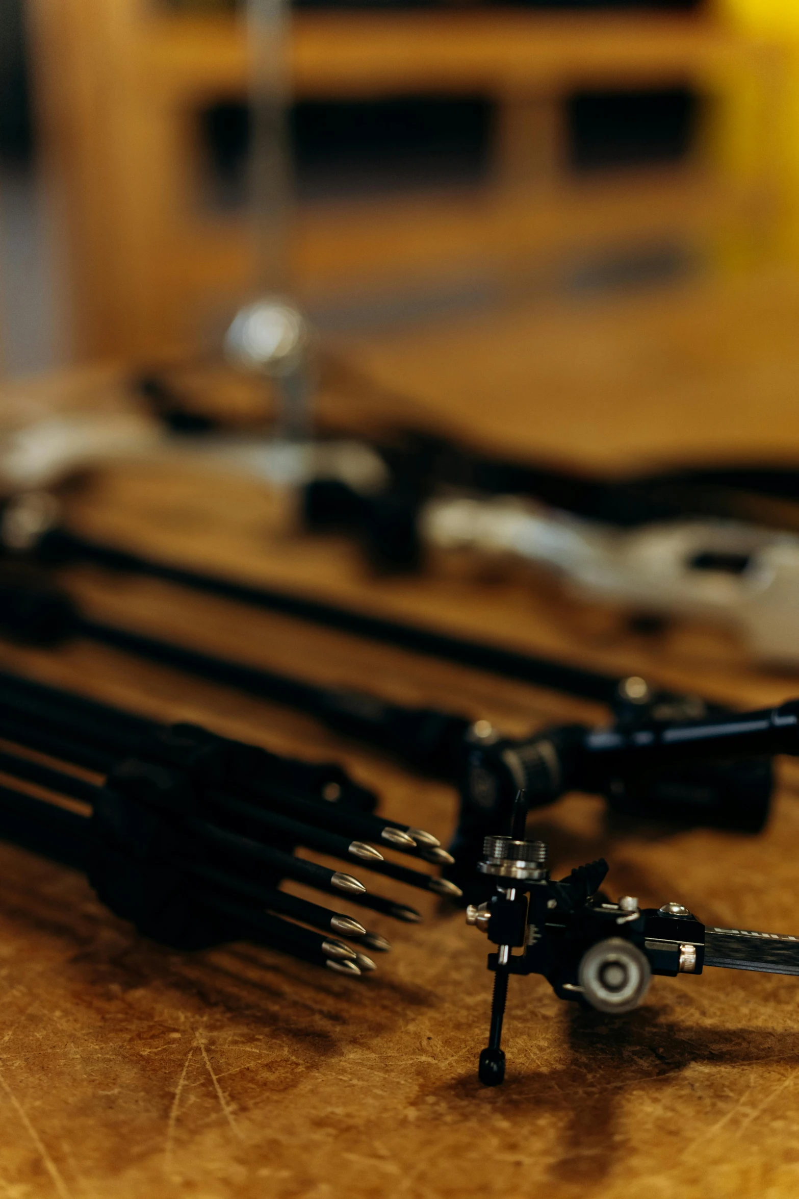 a bunch of tools sitting on top of a wooden table, hold mechanical bow and arrow, shot with sony alpha, robotic arms, close-up shot taken from behind