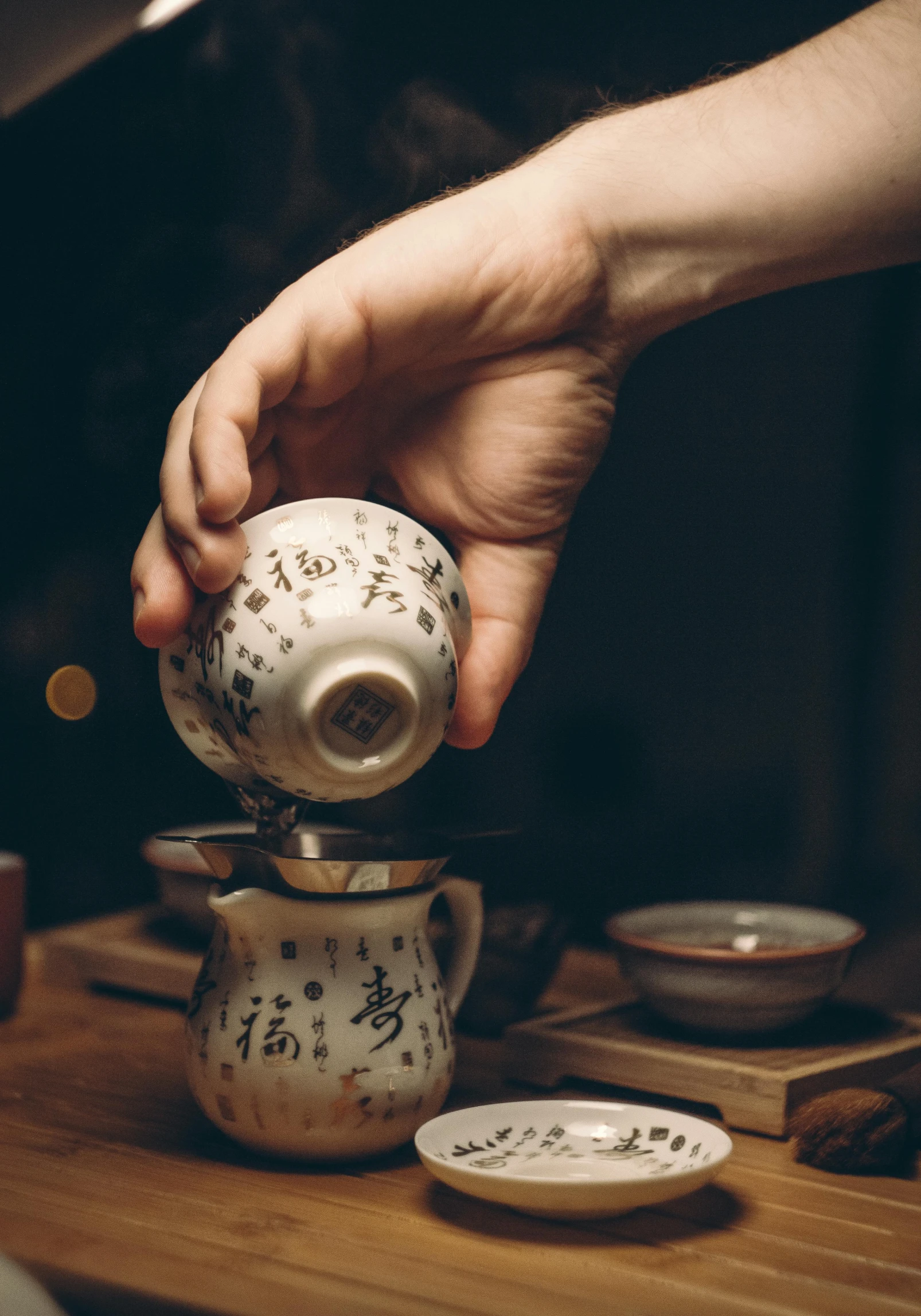 a person pouring tea into a cup on a table, a portrait, inspired by Kanō Shōsenin, trending on unsplash, square, teapots, (night), handwritten