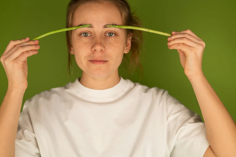 a woman holding a green t - shirt over her head, inspired by Anna Füssli, unsplash, hyperrealism, holding pencil, stalk eyes, low quality photo, scientific photo