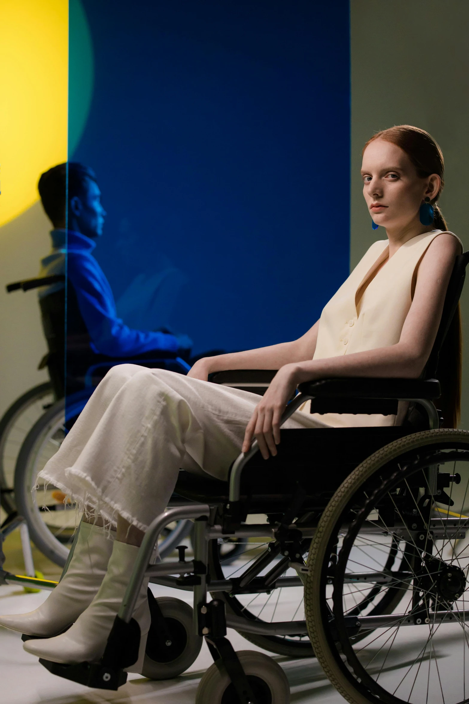 a woman sitting in a wheel chair in a room, an album cover, inspired by Suzanne Duchamp-Crotti, trending on unsplash, hans bellmer and nadav kander, model is wearing techtical vest, evening light, healthcare