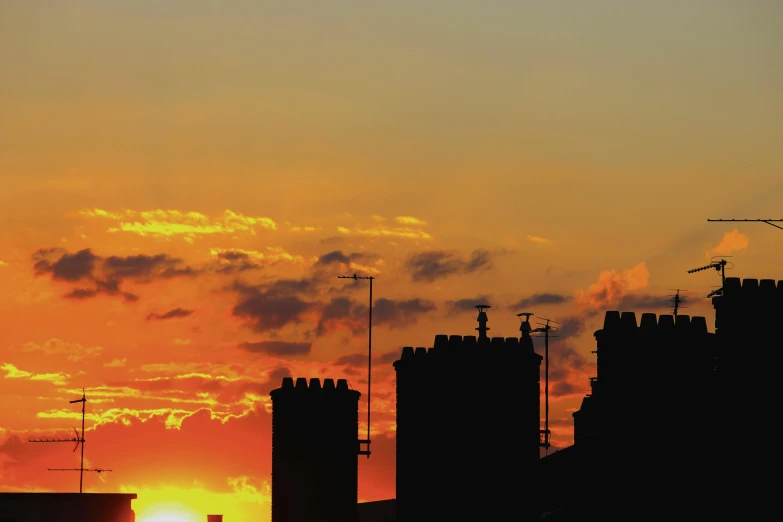 a plane flying over a city at sunset, an album cover, by Ian Fairweather, pexels contest winner, renaissance, chimneys on buildings, silhouette :7, caernarfon castle, shot from roofline