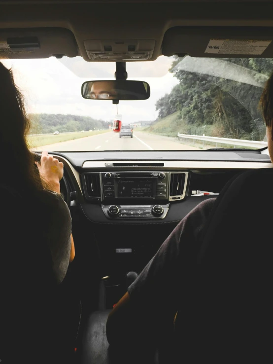 a couple of people that are sitting in a car, facing away from the camera