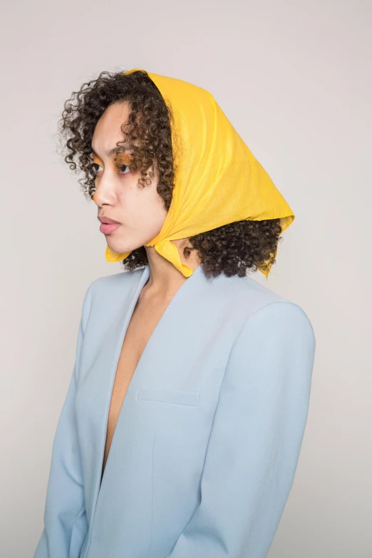 a woman wearing a blue suit and a yellow scarf, an album cover, inspired by Jean-Étienne Liotard, trending on unsplash, curls, hooded, issey miyake, press shot