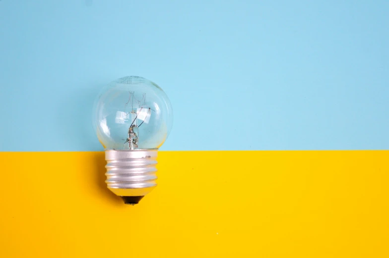 a light bulb sitting on top of a yellow and blue wall, pexels, small in size, thumbnail, 2045