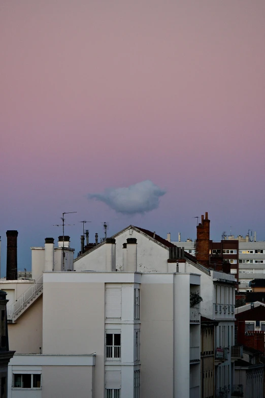 a white building with a pink sky in the background, a photo, inspired by René Magritte, view from distance, fat cloud, buenos aires, in the evening