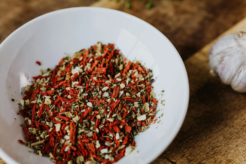 a white bowl sitting on top of a wooden cutting board, a photo, unsplash, hurufiyya, dried herbs, vibrant red and green colours, detailed product image, sparkling