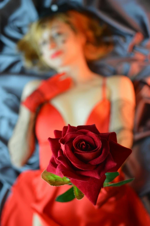 a woman in a red dress holding a rose, inspired by Nan Goldin, shutterstock contest winner, romanticism, lying in bed, wax figure, lobotomy of a beautiful woman, sculpture of a woman