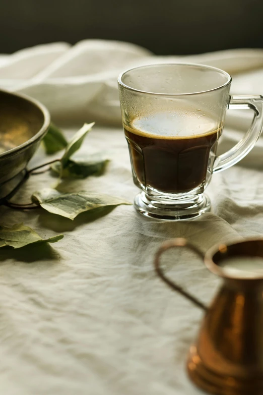 a cup of coffee sitting on top of a table, a still life, inspired by Elsa Bleda, unsplash, renaissance, maple syrup & hot fudge, eucalyptus, glassware, linen