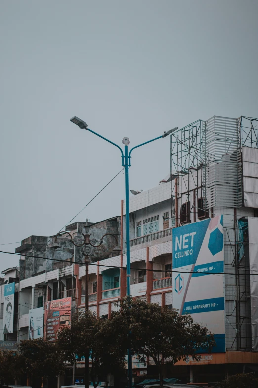 a city street filled with lots of tall buildings, net art, guwahati, sign, under street lamp, nest