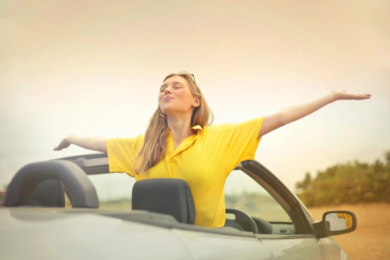 a woman sitting in the driver's seat of a convertible car, pexels contest winner, renaissance, wearing a modern yellow tshirt, female ascending into the sky, avatar image, soft top