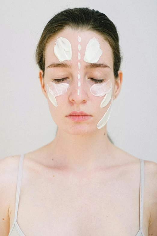 a woman with white paint on her face, by Ellen Gallagher, trending on pexels, renaissance, symmetrical face and full body, photoshoot for skincare brand, white petal, her face hurts