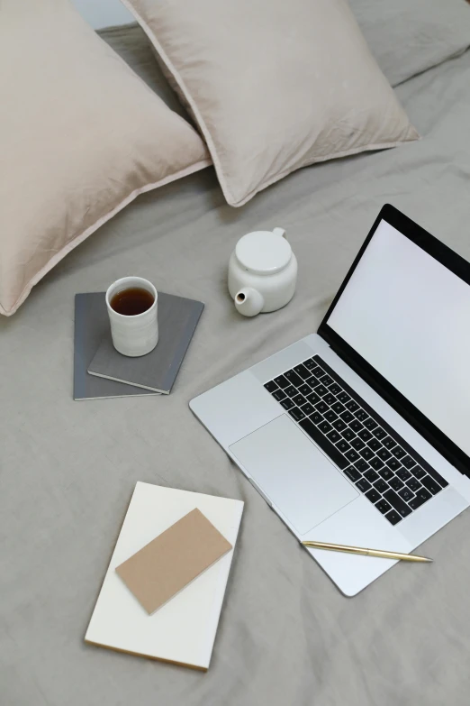 a laptop computer sitting on top of a bed next to a cup of coffee, trending on pexels, light beige pillows, knolling, grey, dwell