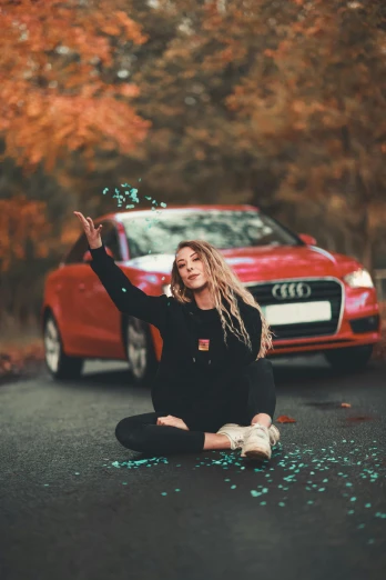 a woman sitting on the ground in front of a red car, pexels contest winner, leafs falling, 😃😀😄☺🙃😉😗, cute girls, square