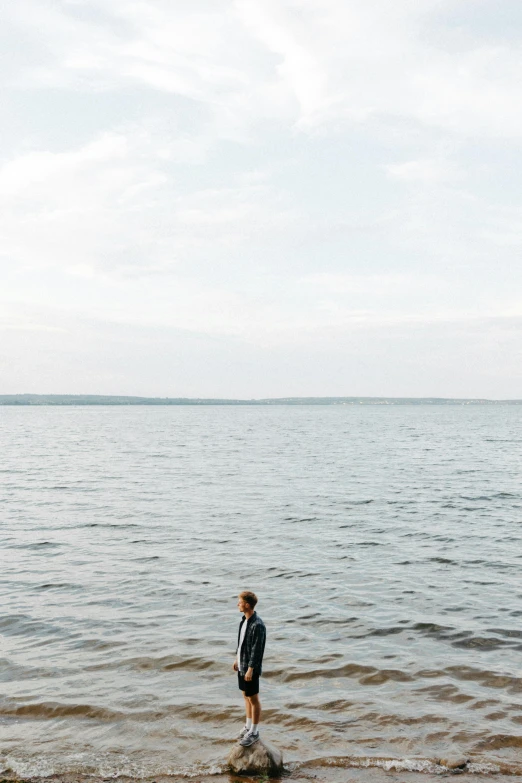 a person standing in a body of water, looking into the distance, connor hibbs, plain background, lakeside