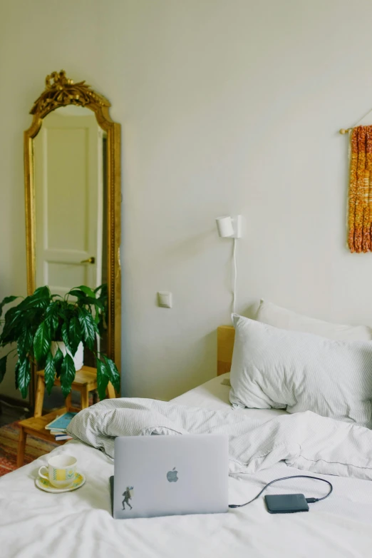 a bed with a laptop sitting on top of it, inspired by Elsa Bleda, trending on unsplash, light and space, mirror reflection, pale yellow walls, lush surroundings, apartment of an art student