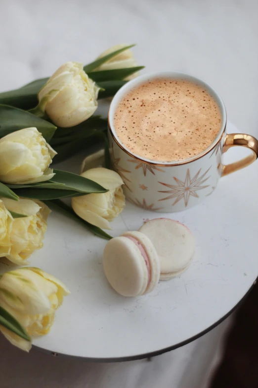 a cup of coffee and some flowers on a table, macaron, ivory and copper, thumbnail, tulip