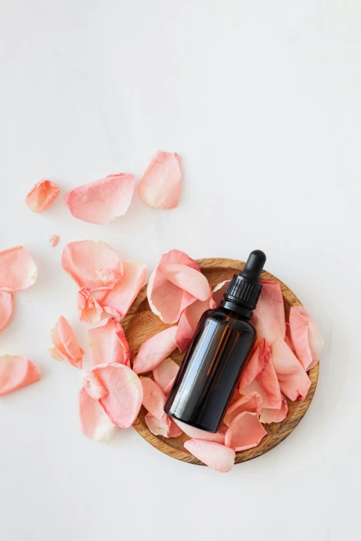 a bottle of essential oil and rose petals on a white background, a picture, by Arabella Rankin, trending on pexels, perky woman made of petals, etsy, skin care, thumbnail