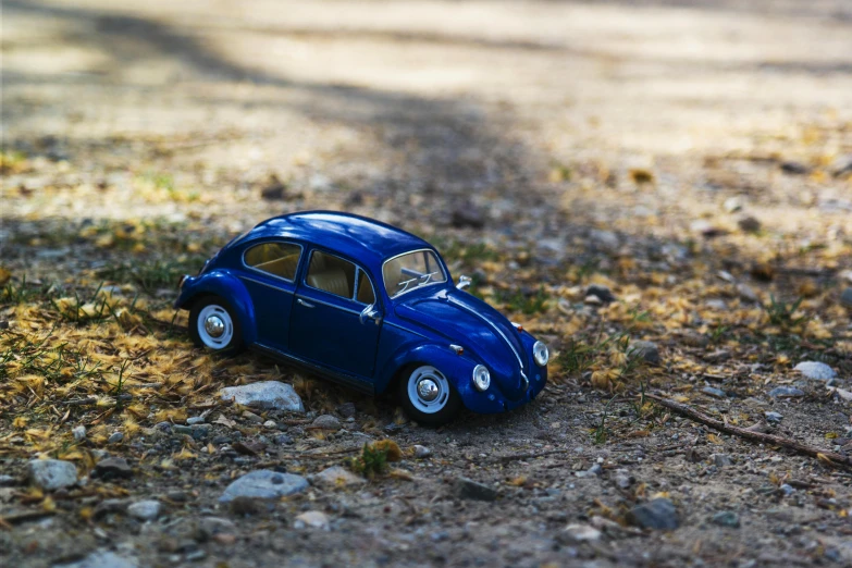 a toy car is sitting on the ground, pexels contest winner, photorealism, beetle-inspired, cobalt blue, in the hillside, high quality photo