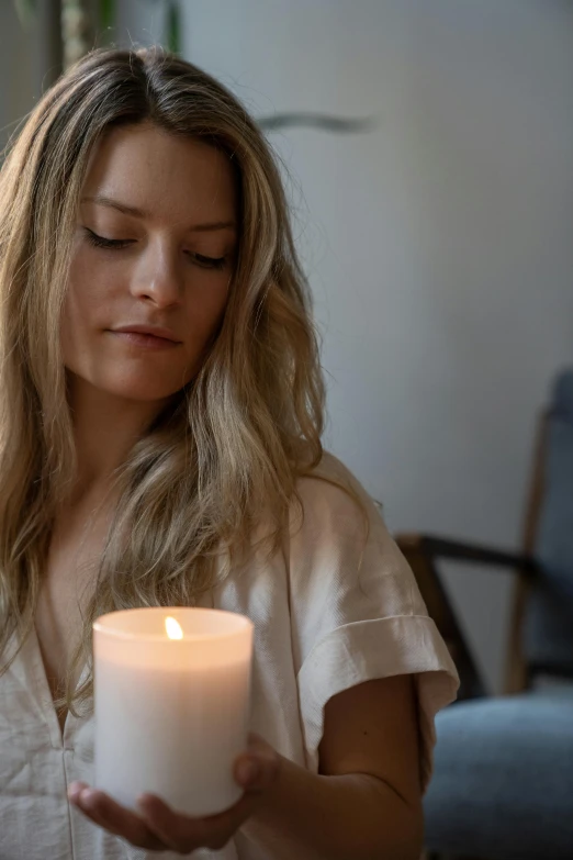 a woman holding a lit candle in her hands, a portrait, trending on unsplash, close up of a blonde woman, contemplative, profile image, multiple stories