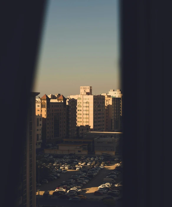 a view of a parking lot from a window, an album cover, inspired by Elsa Bleda, unsplash contest winner, brutalism, moroccan city, tall buildings on the sides, golden hour 8 k, hotel room