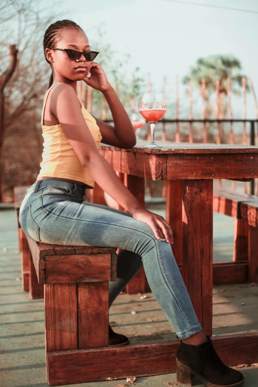 a woman sitting on a wooden bench talking on a cell phone, by Niko Henrichon, pexels contest winner, tight denim jeans, light skinned african young girl, doing a sassy pose, sitting on the table