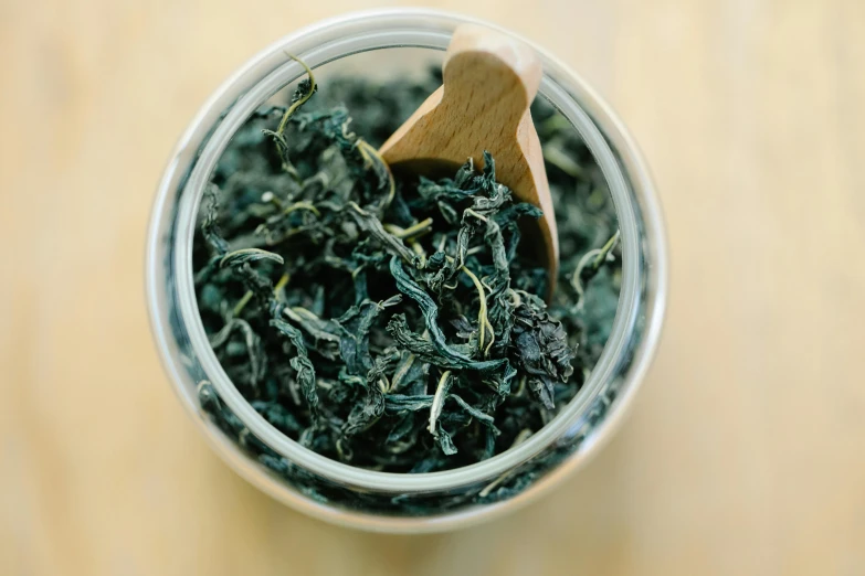 a cup of green tea with a wooden spoon, by Adam Marczyński, pexels, hurufiyya, jar on a shelf, with seaweed, avatar image, flattened