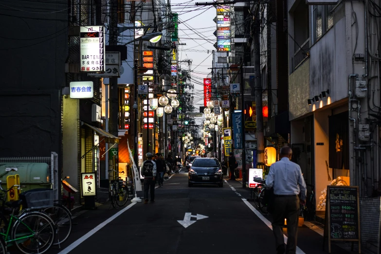 a man riding a bike down a street next to tall buildings, a photo, pexels contest winner, ukiyo-e, warm street lights store front, busy small town street, ethnicity : japanese, a quaint