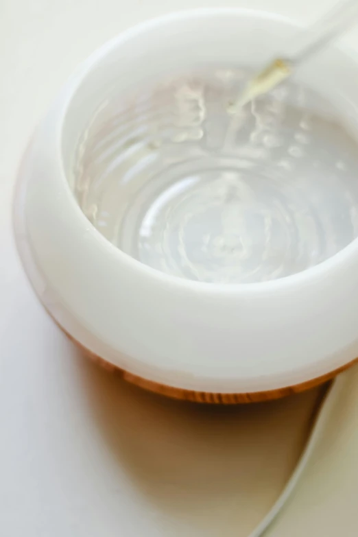 a bowl of liquid with a spoon in it, light wood, closeup of magic water gate, detailed product image, uplight