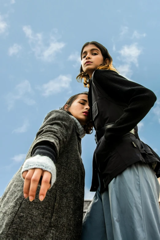 a couple of women standing next to each other, by Niko Henrichon, trending on unsplash, renaissance, z nation, blue sky, rugged black clothes, juno promotional image