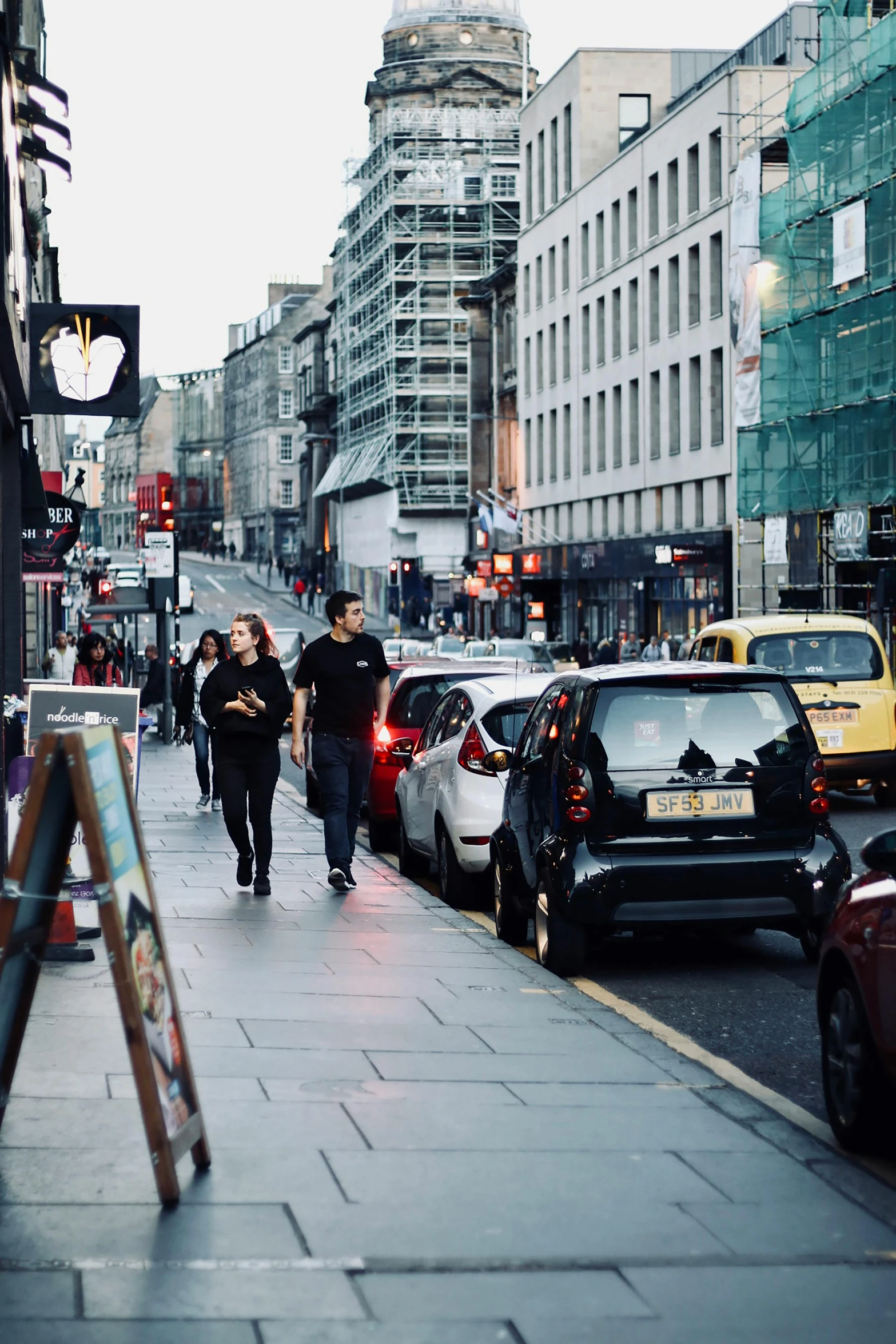 a group of people walking down a city street, by Nick Fudge, trending on unsplash, cars parked, square, glasgow, ilustration