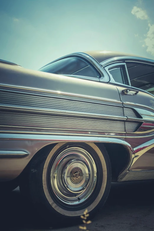 a couple of old cars parked next to each other, a colorized photo, pexels contest winner, retrofuturism, shiny silver with gold trim, close - up profile, tail fin, soft shadowing