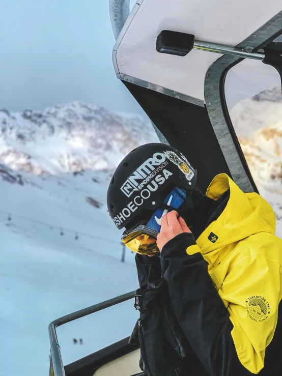 a man riding a ski lift on top of a snow covered slope, black and yellow scheme, phone!! held up to visor, diego fernandez, profile image