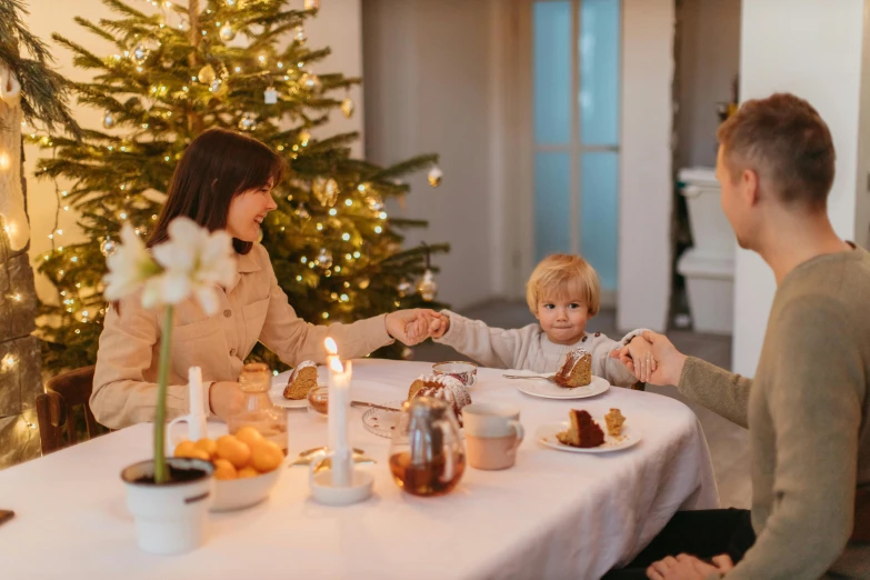 a man and woman sitting at a table with a child, by Emma Andijewska, pexels contest winner, christmas, high quality product image”, dining table, white