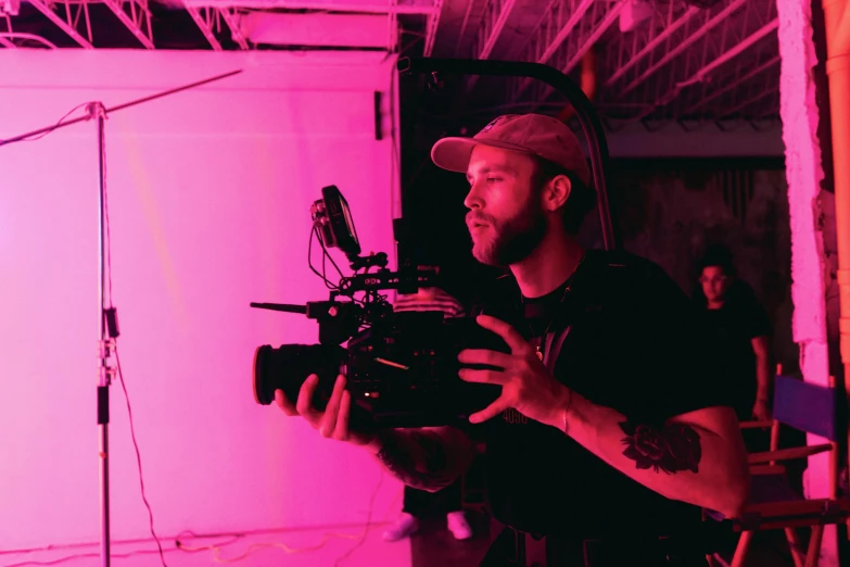 a man holding a camera in front of a pink light, vfx film, behind the scenes, jen bartel, **cinematic