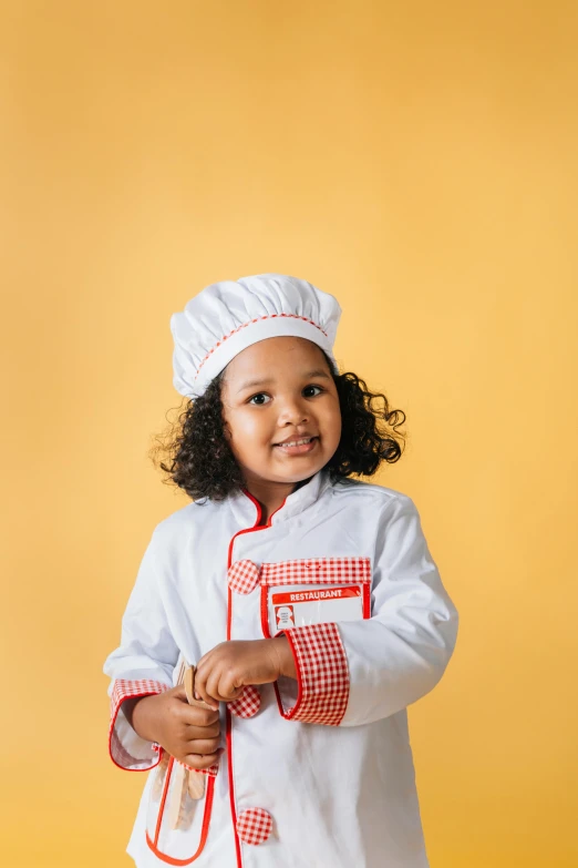 a little girl dressed in a chef's outfit, a picture, by Arabella Rankin, shutterstock contest winner, plain background, mixed race, a handsome, product shot