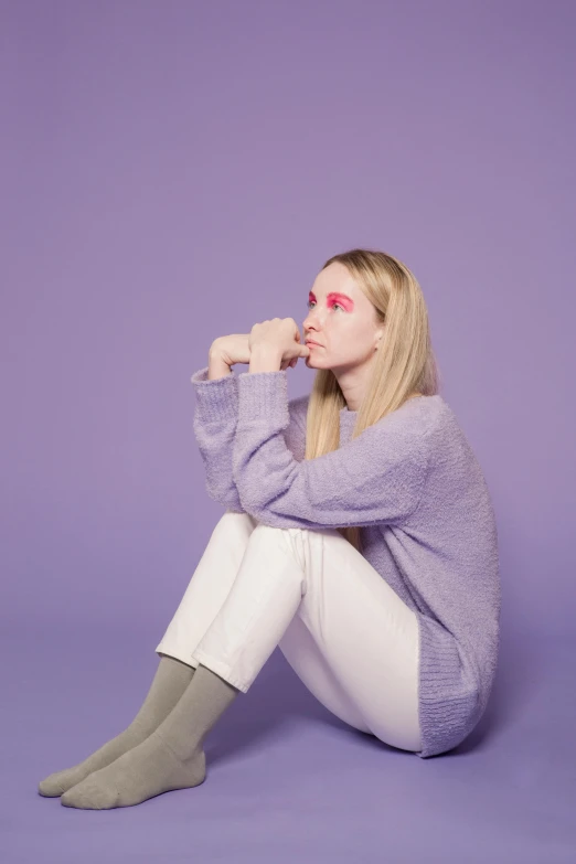 a woman sitting on the ground with her legs crossed, an album cover, inspired by Maud Naftel, pale skin and purple eyes, britt marling style 3/4, looking to the side off camera, solid background