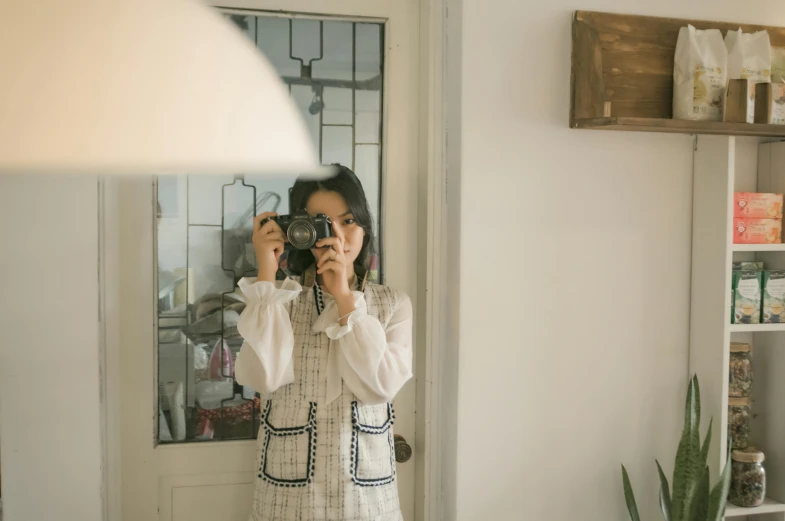 a woman taking a picture of herself in a mirror, a picture, inspired by Elsa Bleda, pexels contest winner, visual art, wearing lab coat and a blouse, korean woman, home album pocket camera photo, wearing jacket and skirt