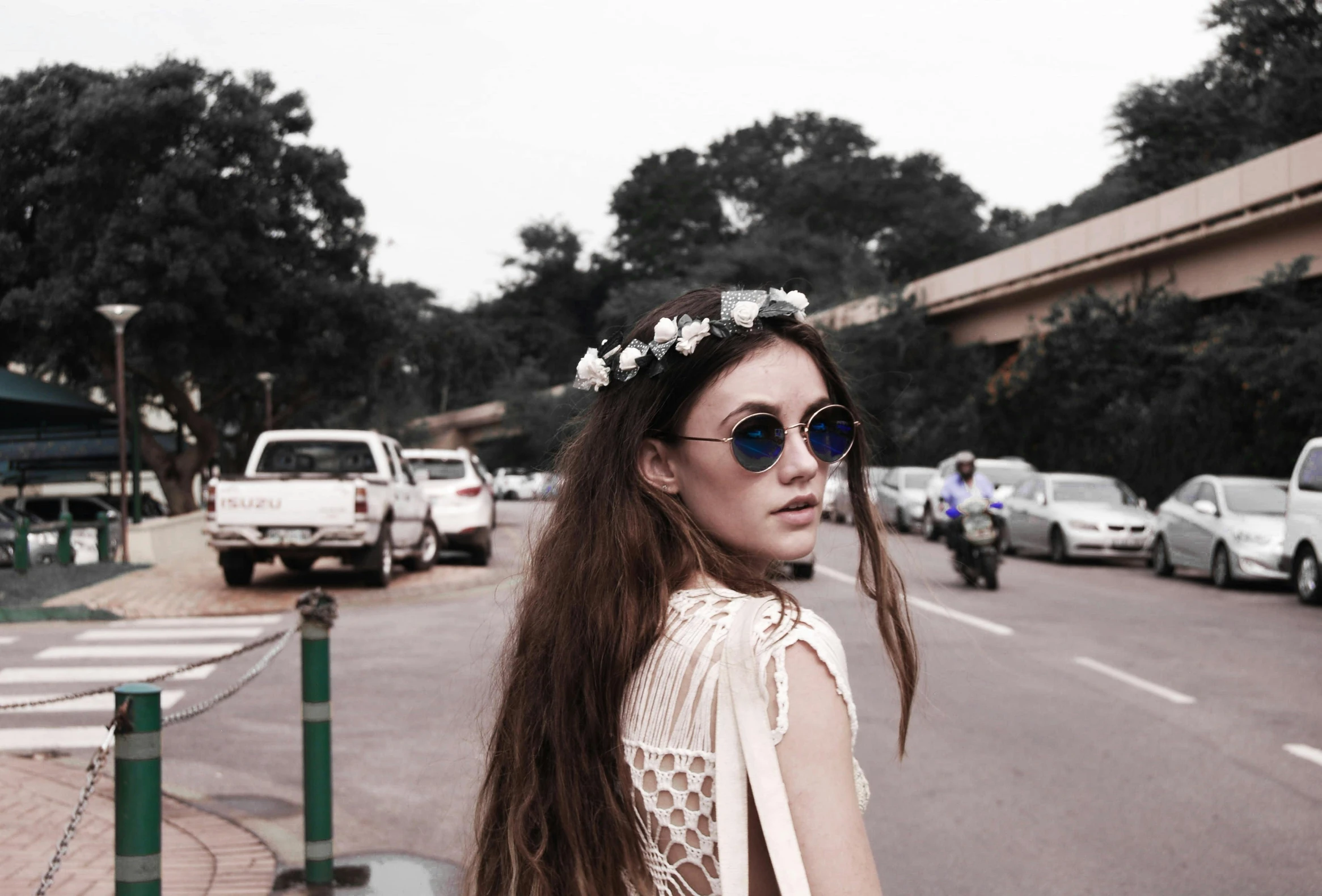 a woman standing on the side of the road, by Lucia Peka, pexels contest winner, photorealism, white flower crown, round sunglasses, ulzzang, girl with plaits