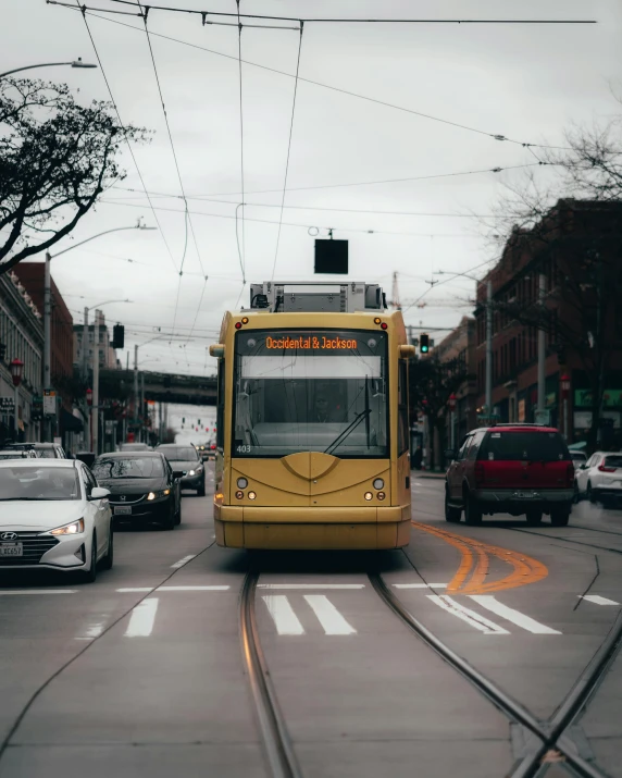 a yellow bus driving down a street next to cars, by Carey Morris, pexels contest winner, trams, lgbt, portland oregon, square