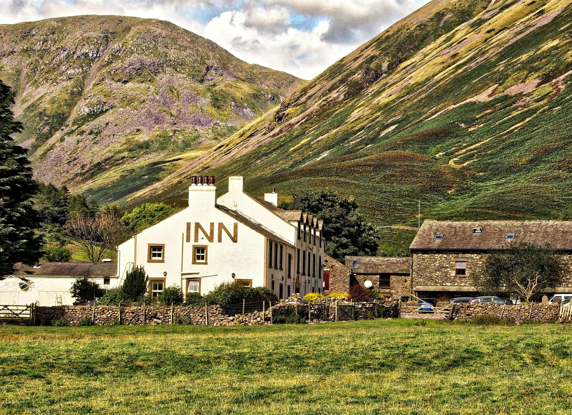 a large white building sitting on top of a lush green field, by Kev Walker, pexels contest winner, tavern, in mountains, glen, in muted colours