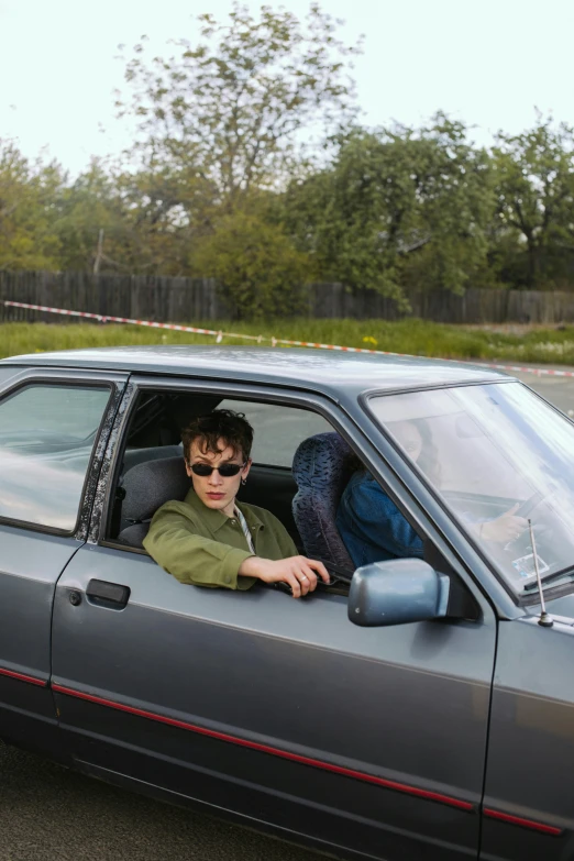 a man sitting in the driver's seat of a car, an album cover, inspired by Nan Goldin, pexels contest winner, renaissance, russian lada car, julian ope, finn wolfhard, hillside