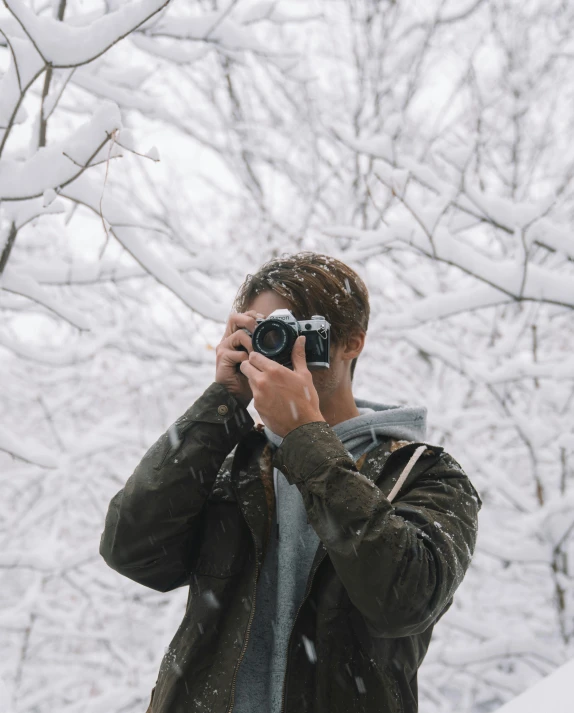 a man taking a picture of himself in the snow, unsplash contest winner, visual art, mid-shot of a hunky, trees in the background, non-binary, cameras lenses