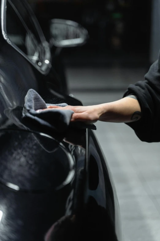 a person cleaning a car with a cloth, matte black, square, professional image, concern